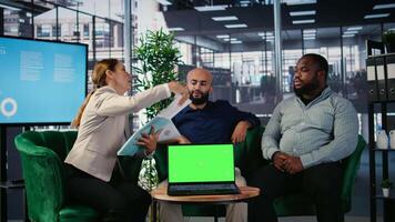 Business people negotiate to align on vision next to mockup display on laptop, using data driven insights and cultural diversity to support leadership and corporate success. Camera A. video
