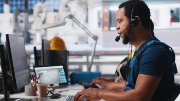 Call center technician handling maintenance inquiries in solar factory, working in customer service industrial tech support. African american operator on headset with clients. Camera A. video