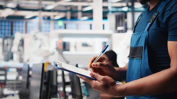 Black photovoltaics factory specialist checking configuration files, analyzing data to ensure seamless production. Solar panels manufacturing plant employee reading user manual. Camera B. video