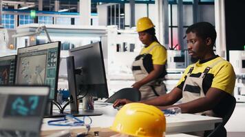 Black engineer works on solar software settings in automated factory, optimizing the production process. Ensures optimal system configuration using digital tools and industrial robotics. Camera B. video