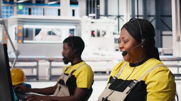 Customer support black engineer at help desk in photovoltaic facility answering calls on headset, offering assistance and support in fixing technical issues. Female operator on help line. Camera B. video
