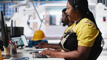 African American engineer offers service from solar panel call center, managing help line requests for support and maintenance. Customer support operator improve factory operations. Camera A. video
