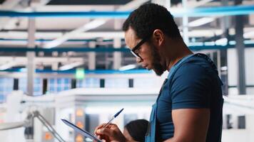 Portrait of engineer in photovoltaics factory reviewing paperwork to diagnose malfunctioning systems. Solar panels plant worker reading inspection data files to reduce downtime. Camera A. video