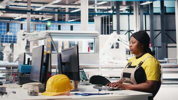Engineer configures solar panel systems on PC in modern factory, working on energy optimization software. Expert manages photovoltaic operations in a high tech, automated facility. Camera A. video