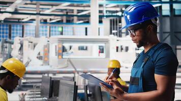 Black photovoltaics factory technician looking over paperwork documents, analyzing data for production. Solar panels manufacturing plant worker reading files to troubleshoot errors. Camera B. video