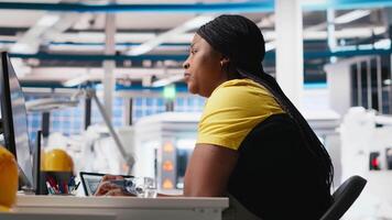 African american engineer analyzes energy consumption software in solar factory, uses PC program to enhance solar cell production and reduce faults in automated machinery systems. Camera A. video