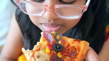 Child enjoys pizza with toppings in bright setting video
