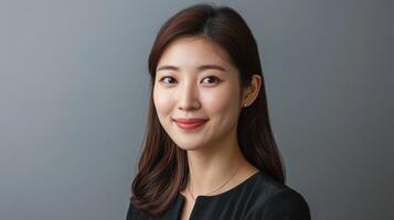 Woman smiles confidently while posing against a neutral gray background in a professional setting photo