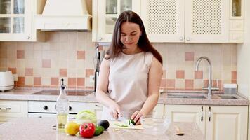beautiful Woman in bright kitchen slicing cucumber and singing while making a fresh salad video