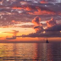 A sailboat is sailing in the ocean at sunset photo