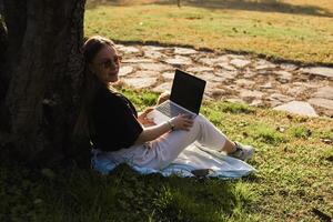 Cocker spaniel enjoys a sunny afternoon with its owner who works on a laptop in the park photo