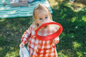 Girl Child plays with a red strainer during a picnic on a sunny day in a park photo