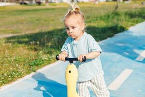 Young child riding a scooter on a sunny day in park setting photo