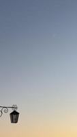 Serene evening sky with crescent moon above vintage lantern in minimalistic composition reflecting calm and simplicity of dusk time photo
