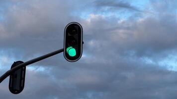 Green traffic light against cloudy sky symbolizing go or forward movement with urban infrastructure and road safety elements photo