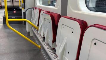 Folded red and white bus seats with yellow handrails inside an empty modern vehicle interior photo