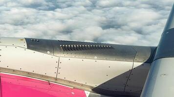 Striking view of an airplane wing and engine above a sea of white clouds captured during flight with sunlit metal surface photo