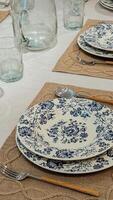 Elegant table setting with blue floral plates, rustic burlap placemats, and glassware creating a charming dining atmosphere photo