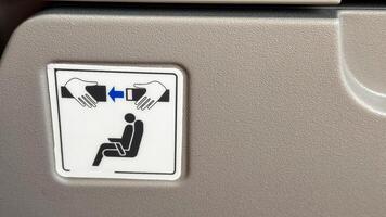 Safety sign on airplane seatback conveying the importance of seatbelt security for passengers highlighted with simple instructional graphics photo