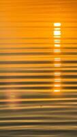 Golden sunset reflection on calm water surface with soft ripples creating a tranquil and serene ambiance capturing nature's beauty photo