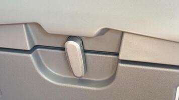 Airplane tray lock close-up featuring gray plastic surface and lever mechanism creating a minimalistic industrial design element photo