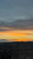 Dramatic sunset over a quiet town with vibrant sky and horizon silhouette in the evening with soft clouds illuminated by golden light photo