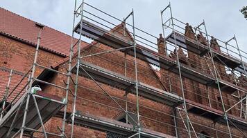 Scaffolding surrounds historic brick building under restoration on a cloudy day showcasing architectural details and renovation work photo