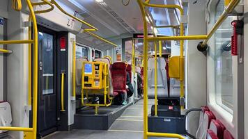 Modern urban train interior with yellow handrails and red seating on a daytime commute in a spacious and clean environment photo