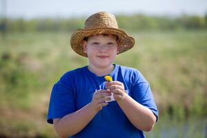 Portrait of a funny teenage boy in a straw hat against the backdrop of summer nature. A freckled boy in the summer. photo