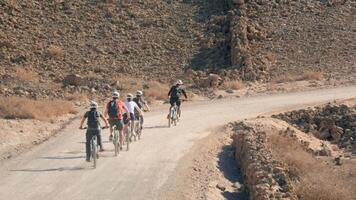 Cyclists navigating a winding desert trail during daylight video
