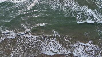 Waves crashing softly on a serene beach during midday with sunlight dancing on the water video