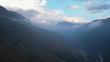 Aerial view of mountain valley with dramatic clouds at dusk video