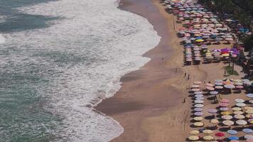 Aerial view of a beach with colorful umbrellas and waves in Bali video