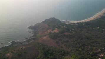 Green forested cliffs and open ocean seen from above in Goa video