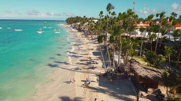 Aerial view of a tropical beach near a hotel with many tourists in Punta Cana, Dominican Republic. People are relaxing, sunbathing, and swimming video