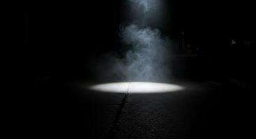 A dark street with a light shining on it photo