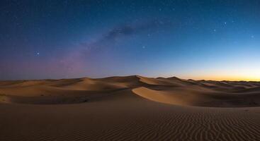 A desert with sand dunes and a sky full of stars photo