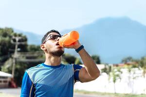Sport man drinking in an orange bottle with bpa free. photo