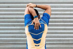 Back view of a young hispanic male doing arm exercises in front of a garage door photo