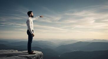 A man standing on top of a mountain pointing at something photo