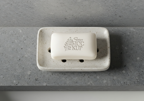 A bar of soap sits in a speckled rectangular soap dish on a gray countertop psd