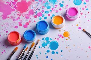Paintbrushes and gouache jars creating colorful splashes on white background photo