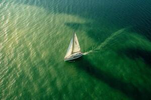 Sailboat sailing on green water in the sea, aerial view photo