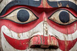 Close-up of traditional totem pole showing colorful carvings and native art photo