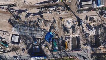 Aerial view of construction zones with cranes, concrete mixers, and machinery in motion. Trenches, pillars, and materials visible in an urban setting. video