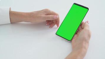 Smartphone with Green Screen Chroma key in Female Hands on White Table, Touching Display, Exploring Mobile Functions, Digital Technology Concept, Online Connectivity, Application Personalization video