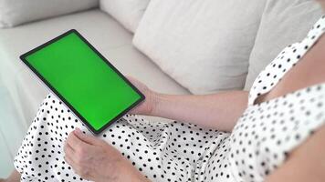 Modern Digital Lifestyle with Woman Sitting Comfortably on Sofa, Holding Tablet with Green Screen, Navigating Mobile Apps, Scrolling, Browsing, Interactive Touch screen, Cozy Atmosphere video