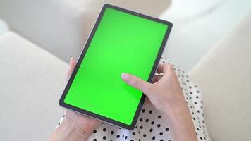 oben Aussicht Hand halt packend Tablette mit beschwingt Grün Bildschirm, einnehmend mit interaktiv Anzeige im heim. Digital Attrappe, Lehrmodell, Simulation zum Bildschirm Ersatz, präsentieren Chroma Schlüssel Technologie im Innen- Rahmen video
