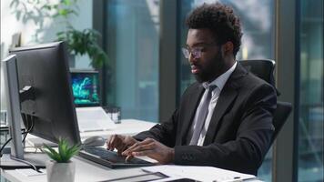 Confident happy African American man working typing computer pc manager office worker male looking at camera smiling businessman business employer entrepreneur online work guy nodding head programmer video