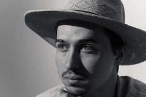 Captivating portrait of a young man in a woven hat, showcasing deep contemplation and artistic expression in soft light photo